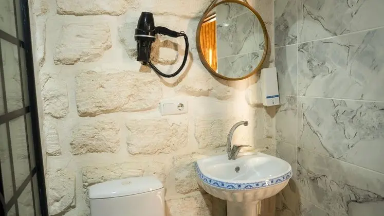 Harmel Odası: Şık Bir Ayna, Saç Kurutma Makinesi Ve Taş Mimariyle Uyumlu Modern Lavabo Alanı.